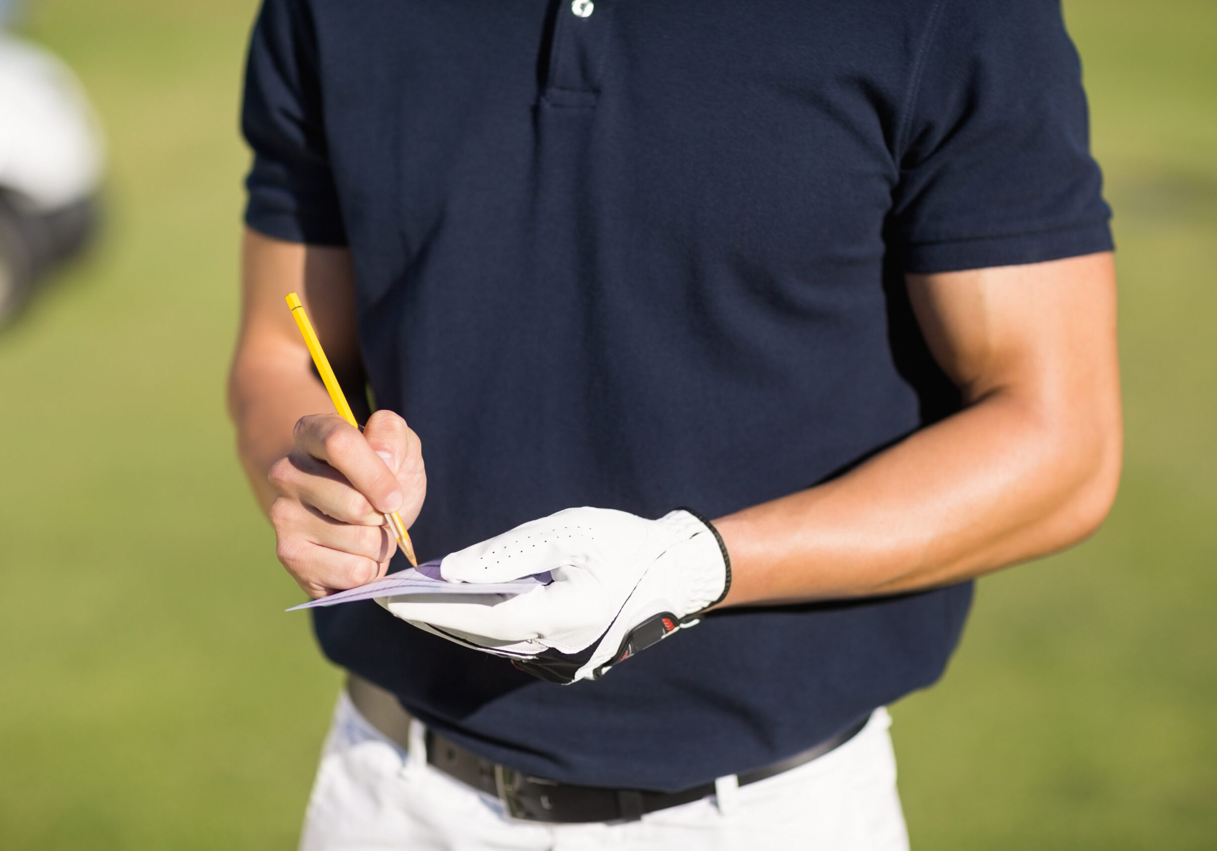 Midsection,Of,Golfer,Writing,On,Score,Card,While,Standing,At