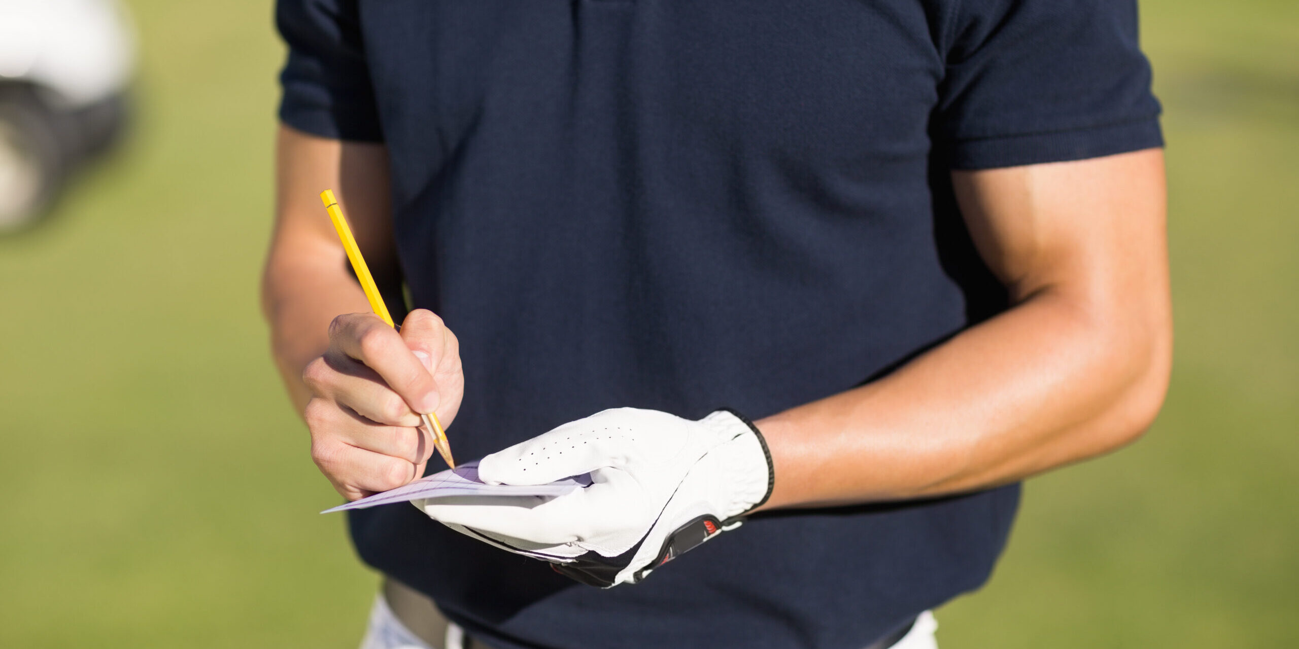 Midsection,Of,Golfer,Writing,On,Score,Card,While,Standing,At
